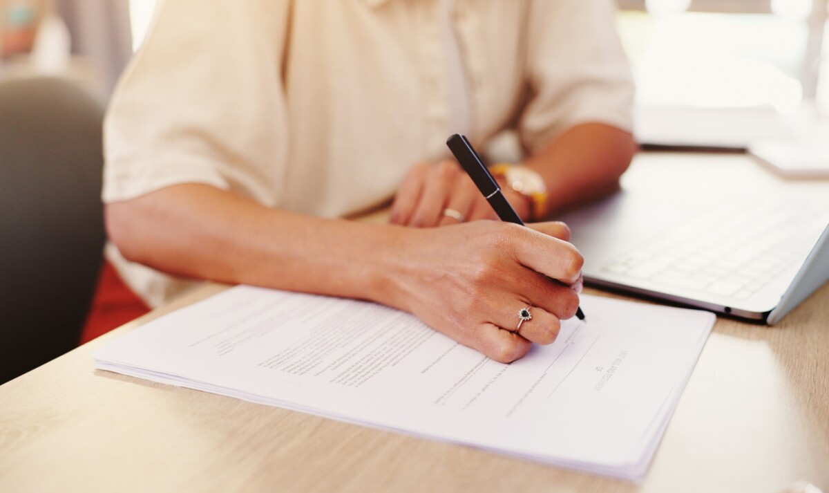 Closeup, laptop and businesswoman with paperwork for signature, agreement and compliance for loan.